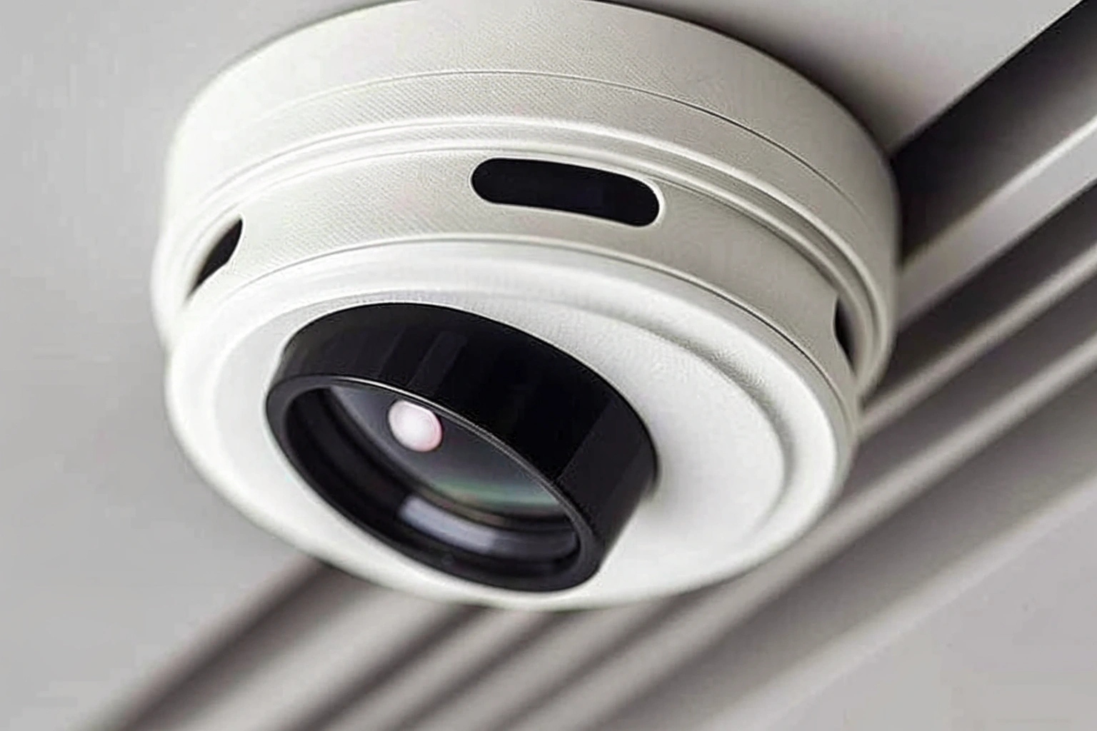 Gros plan sur un détecteur de fumée avec un minuscule point noir suspect indiquant la présence d'un objectif de caméra caché.